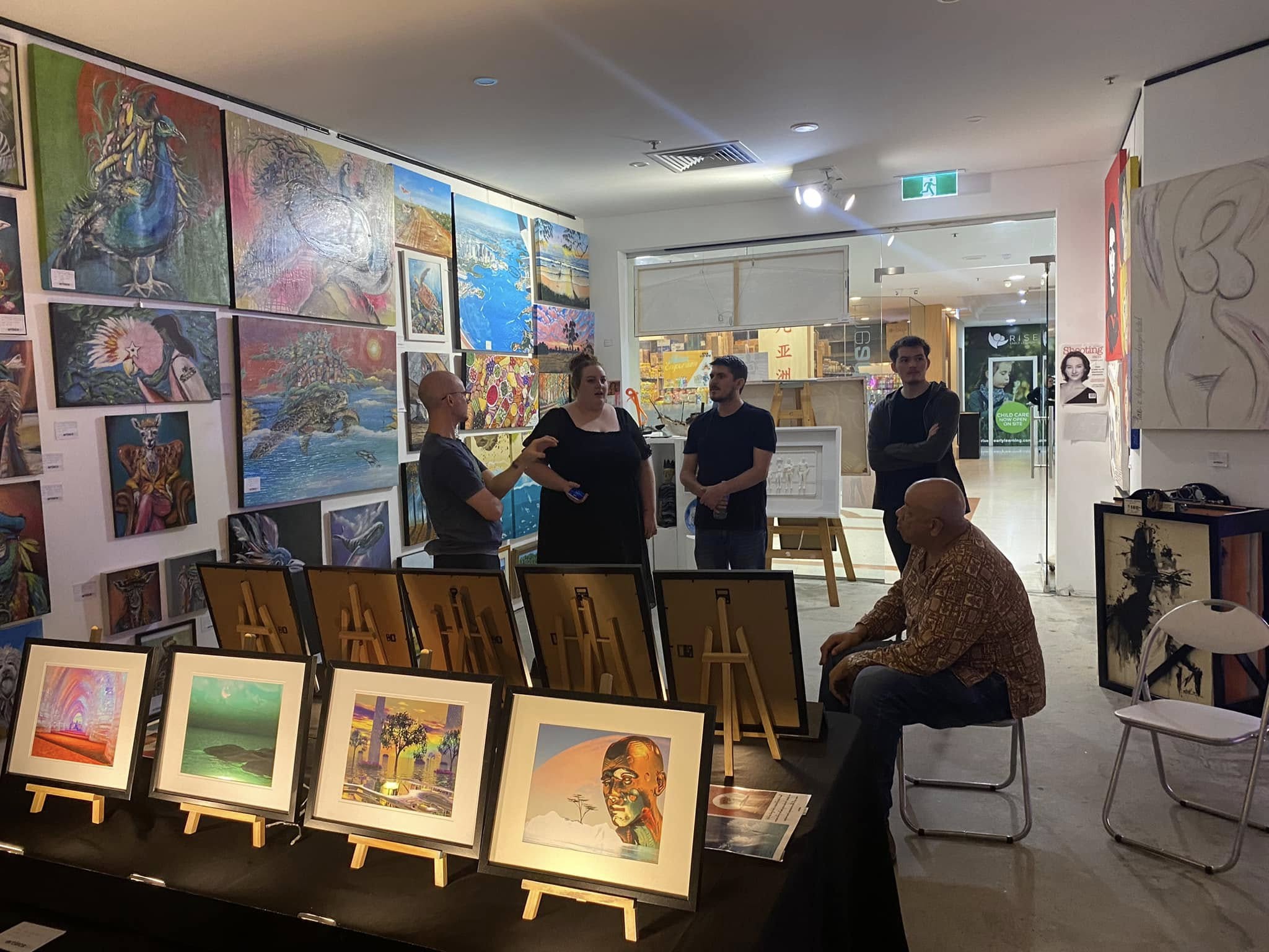 Visitors gathering inside the Gold Coast exhibition space with artwork covering the walls
