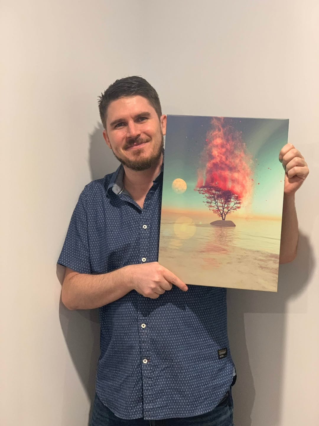 Jay Salton holding a luminous tree artwork at his Gold Coast exhibition